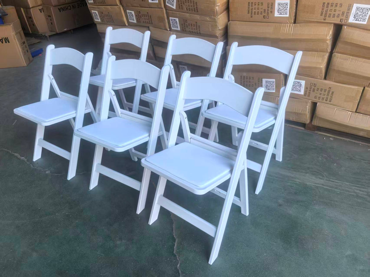 Five white folding chairs assembled for inspection — pad dents visible on every seat